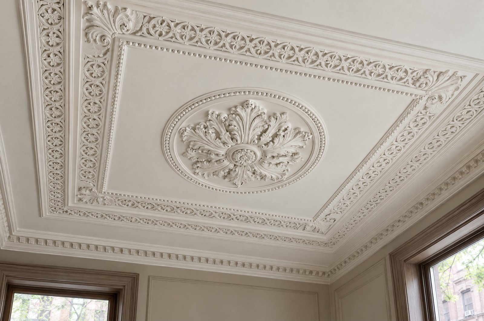 A restored plaster ceiling with a central medallion inside a beaded, enriched panel